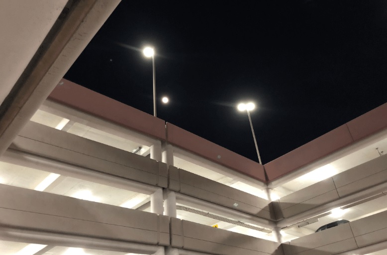 large parking garage with tall light poles on top deck