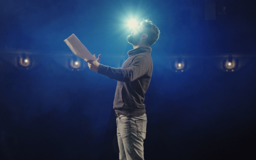 actor performing a monologue on stage with lights visible